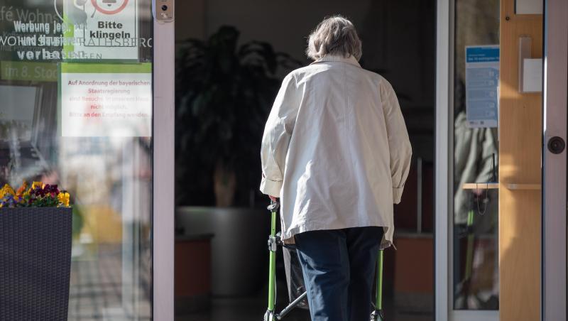 Eine Seniorin betritt mit ihrer Gehhilfe den Eingang eines Senioren-Wohnstifts. Eine Seniorin betritt mit ihrer Gehhilfe den Eingang eines Senioren-Wohnstifts.