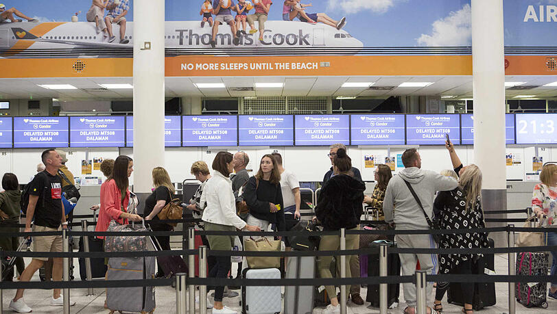 Urlauber stehen an einem Check-In-Schalter von Thomas Cook im Südterminal des Flughafens Gatwick. Urlauber stehen an einem Check-In-Schalter von Thomas Cook im Südterminal des Flughafens Gatwick.