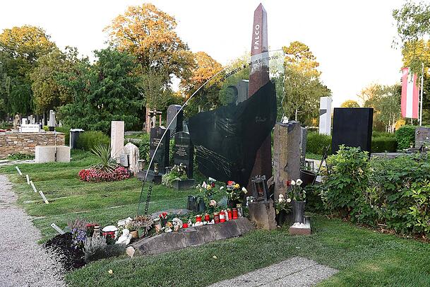 Falcos Grabstätte besteht aus drei zentralen Komponenten: eine Glasplatte (symbolisiert sein Werk), ein Obelisk (steht für den Künstler) und eine Säule (symbolisiert die Privatperson). Falcos Grabstätte besteht aus drei zentralen Komponenten: eine Glasplatte (symbolisiert sein Werk), ein Obelisk (steht für den Künstler) und eine Säule (symbolisiert die Privatperson).