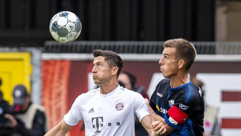 Münchens Robert Lewandowski und Paderborns Uwe Hünemeier (l-r.) im Zweikampf um den Ball. Foto: David Inderlied Münchens Robert Lewandowski und Paderborns Uwe Hünemeier (l-r.) im Zweikampf um den Ball. Foto: David Inderlied