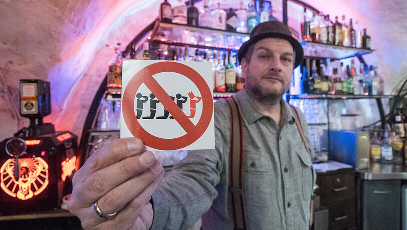 Kneipier Martin Stein zeigt in Regensburg einen Aufkleber, der auf die Junggesellenabschiedsfreie Zone in seiner Bar hinweist. Kneipier Martin Stein zeigt in Regensburg einen Aufkleber, der auf die Junggesellenabschiedsfreie Zone in seiner Bar hinweist.