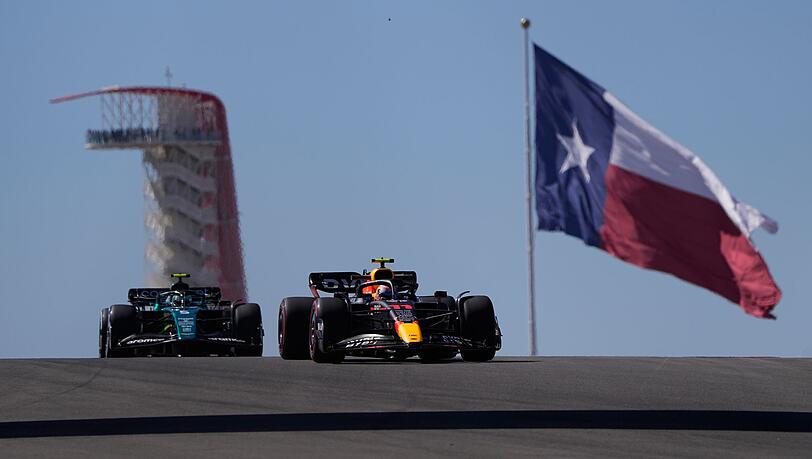 MotoRed-Bull-Pilot Sergio Perez (r) aus Mexiko, und Aston-Martin-Pilot Sebastian Vettel (l) aus Deutschland, steuern durch eine Kurve vor der Flagge von Texas. MotoRed-Bull-Pilot Sergio Perez (r) aus Mexiko, und Aston-Martin-Pilot Sebastian Vettel (l) aus Deutschland, steuern durch eine Kurve vor der Flagge von Texas.