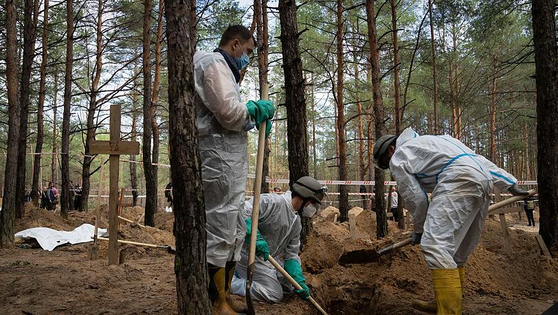 Arbeiter stehen auf dem Waldfriedhof von Isjum am Grab eines nicht identifizierten Zivilisten. Dort wurden nach Angaben aus Kiew mehr als 400 Leichen gefunden. Die Menschen sollen ums Leben gekommen sein, als Russland die Stadt Ende März beschoss. Arbeiter stehen auf dem Waldfriedhof von Isjum am Grab eines nicht identifizierten Zivilisten. Dort wurden nach Angaben aus Kiew mehr als 400 Leichen gefunden. Die Menschen sollen ums Leben gekommen sein, als Russland die Stadt Ende März beschoss.