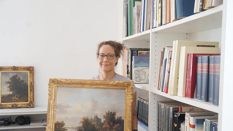Christiane Pelikan, eine Mitarbeiterin des Auktionshauses, zeigt eines der Gemälde, die versteigert werden. Christiane Pelikan, eine Mitarbeiterin des Auktionshauses, zeigt eines der Gemälde, die versteigert werden.