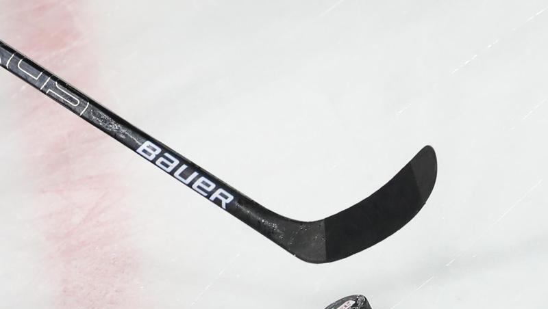Ein Puck liegt vor einem Schläger auf dem Eis. Ein Puck liegt vor einem Schläger auf dem Eis.