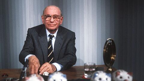 "Welches Schweinderl hätten Sie denn gern?": Quizmaster Robert Lembke 1985 mit den berühmten "Was bin ich?"-Sparschweinen. "Welches Schweinderl hätten Sie denn gern?": Quizmaster Robert Lembke 1985 mit den berühmten "Was bin ich?"-Sparschweinen.