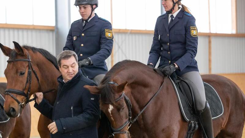 Markus Söder (CSU), Ministerpräsident von Bayern, steht neben den Polizeireitern Robin Philipp mit Pferd Hermes und Stephanie Sendker mit Pferd Noris bei der Vorstellung der neuen Reitergruppe der mittelfränkischen Polizei. Foto: Daniel Karmann Markus Söder (CSU), Ministerpräsident von Bayern, steht neben den Polizeireitern Robin Philipp mit Pferd Hermes und Stephanie Sendker mit Pferd Noris bei der Vorstellung der neuen Reitergruppe der mittelfränkischen Polizei. Foto: Daniel Karmann