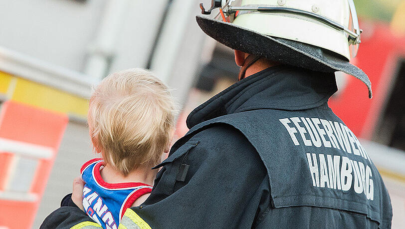 Ein Feuerwehrmann bringt ein Kind in Sicherheit. Bei dem Brand in einem ehemaligen Bunker sind zahlreiche Menschen verletzt worden. Ein Feuerwehrmann bringt ein Kind in Sicherheit. Bei dem Brand in einem ehemaligen Bunker sind zahlreiche Menschen verletzt worden.
