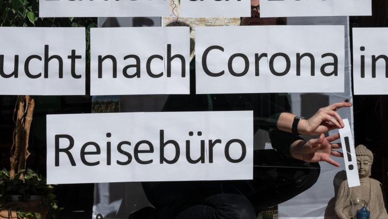 Ein Mitarbeiterin klebt Blätter mit der Aufschrift „Bucht nach Corona im Reisebüro“ in das Schaufenster. Foto: Bernd Thissen/dpa Ein Mitarbeiterin klebt Blätter mit der Aufschrift „Bucht nach Corona im Reisebüro“ in das Schaufenster. Foto: Bernd Thissen/dpa