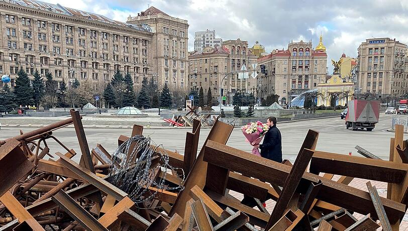 Am Valentinstag läuft ein Mann mit einem Blumenstrauß in der Hand auf dem Maidan-Platz in Kiew an Panzersperren vorbei. Am Valentinstag läuft ein Mann mit einem Blumenstrauß in der Hand auf dem Maidan-Platz in Kiew an Panzersperren vorbei.