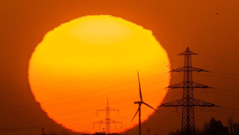 Die Sonne geht hinter Windrädern und Hochspannungsleitungen auf. Die Sonne geht hinter Windrädern und Hochspannungsleitungen auf.