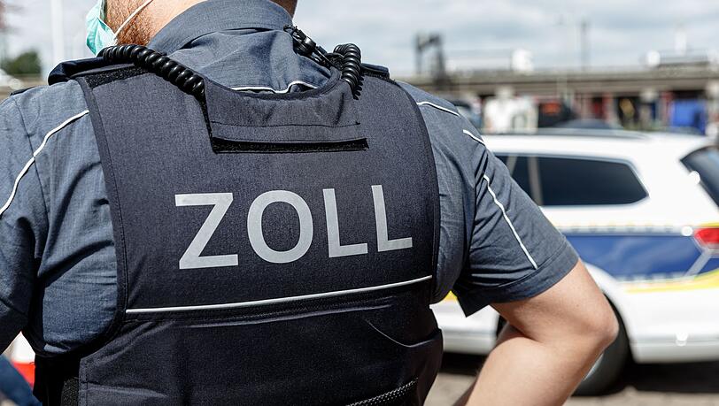 Ein Beamter trägt während seines Dienstes eine Schutzweste mit der Rückenaufschrift "Zoll". Ein Beamter trägt während seines Dienstes eine Schutzweste mit der Rückenaufschrift "Zoll".