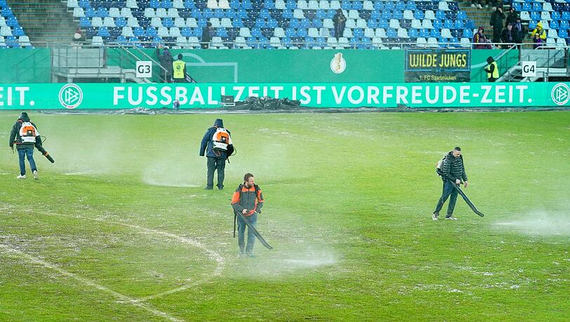 Arbeiter versuchten, Wasserlachen vom Spielfeld im Ludwigsparkstadion zu entfernen. Arbeiter versuchten, Wasserlachen vom Spielfeld im Ludwigsparkstadion zu entfernen.