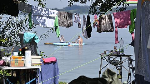 Wäsche hängt auf einem Campingplatz am Chiemsee auf der Leine vor einem Wohnmobil. Die Tourismusbranche will die Gästezahlen bayernweit besser verteilen. Wäsche hängt auf einem Campingplatz am Chiemsee auf der Leine vor einem Wohnmobil. Die Tourismusbranche will die Gästezahlen bayernweit besser verteilen.