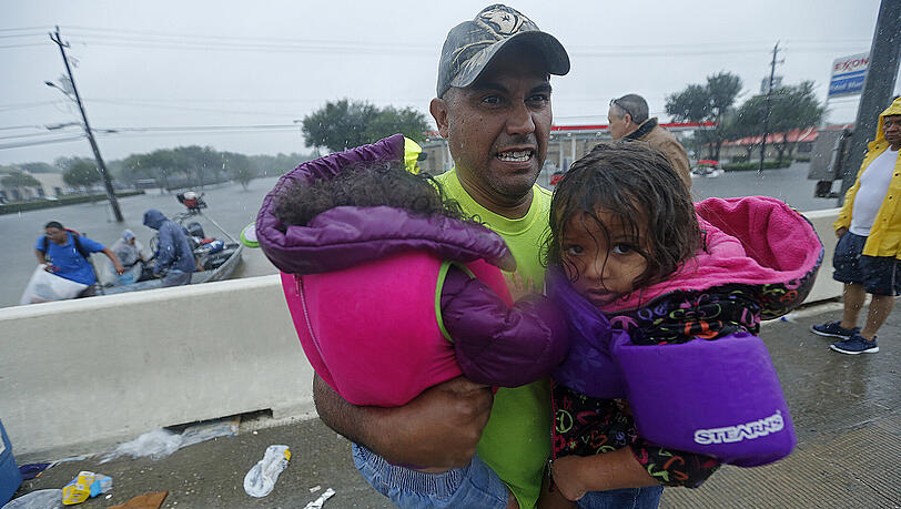 Ein Mann trägt in Houston Kinder, nachdem sie von Feuerwehrleuten aus dem in der Folge des Tropensturms Harvey überfluteten Gebiet gerettet worden waren. Ein Mann trägt in Houston Kinder, nachdem sie von Feuerwehrleuten aus dem in der Folge des Tropensturms Harvey überfluteten Gebiet gerettet worden waren.