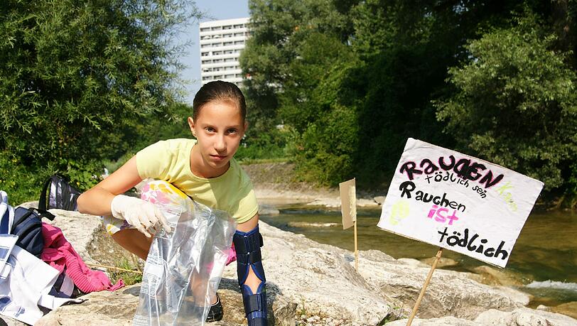 Louisa sammelt fleißig Zigarettenkippen zwischen den Felsen auf, die andere einfach liegenlassen haben. Louisa sammelt fleißig Zigarettenkippen zwischen den Felsen auf, die andere einfach liegenlassen haben.