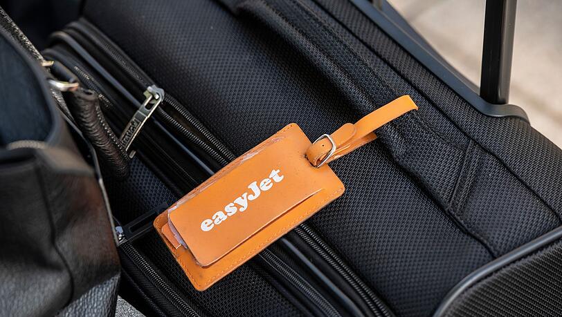 Ein Adressanhänger mit dem Logo von Easyjet ist an einem Koffer befestigt. Ein Adressanhänger mit dem Logo von Easyjet ist an einem Koffer befestigt.