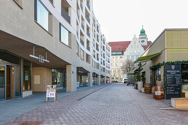 Wo einst ein Umspannwerk der Stadtwerke stand, ist jetzt der Neubau mit Geschäften, Büros und Wohnungen fertig - und wirft Schatten auf den neuen Elisabethmarkt. Unten ist das neue Wirtshaus Eli eingezogen, daneben eine Apotheke und ein sehr großer Brautmodeladen.