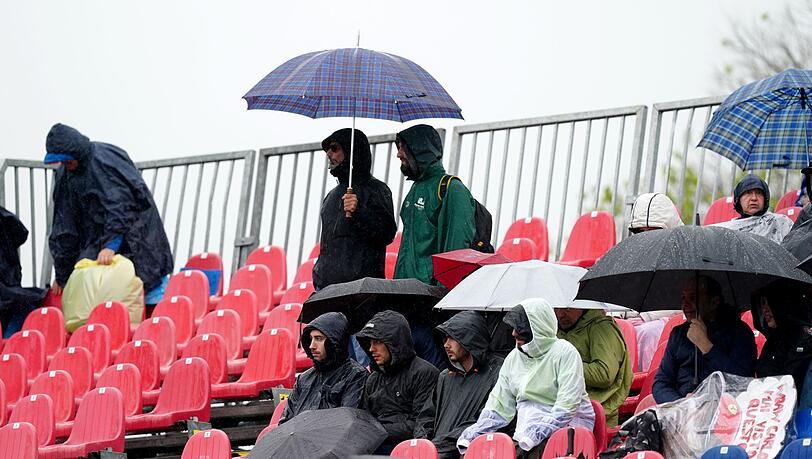 Fans sitzen während des Freien Trainings mit Regenschirmen auf der Tribüne. Fans sitzen während des Freien Trainings mit Regenschirmen auf der Tribüne.
