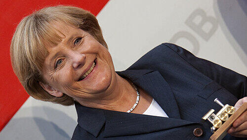 Die Bundeskanzlerin als Bahnfan: Angela Merkel hält eine kleine, vergoldete Modell-Lokomotive in der Hand. Die Bundeskanzlerin als Bahnfan: Angela Merkel hält eine kleine, vergoldete Modell-Lokomotive in der Hand.