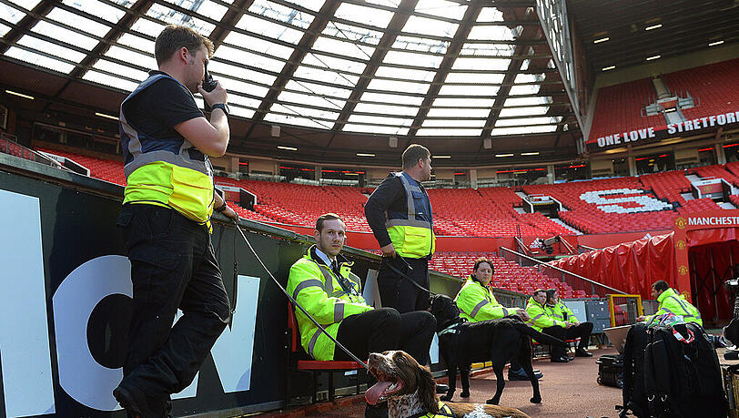 Leere Tribünen im Old-Trafford-Stadion von Manchester United. Sicherheitskräfte und Spürhunde sind im Einsatz. Leere Tribünen im Old-Trafford-Stadion von Manchester United. Sicherheitskräfte und Spürhunde sind im Einsatz.