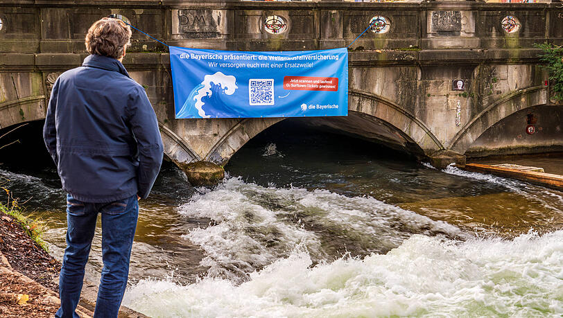 Mit einem großen Banner wirbt "Die Bayerische" an der Eisbachwelle für ihr Gewinnspiel. Mit einem großen Banner wirbt "Die Bayerische" an der Eisbachwelle für ihr Gewinnspiel.