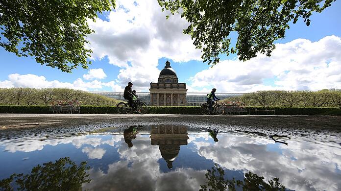 Was für ein Kunstwerk im Hofgarten: Staatskanzlei, Radler, Wolken und blauer Himmel spiegeln sich in einer Pfütze. Was für ein Kunstwerk im Hofgarten: Staatskanzlei, Radler, Wolken und blauer Himmel spiegeln sich in einer Pfütze.