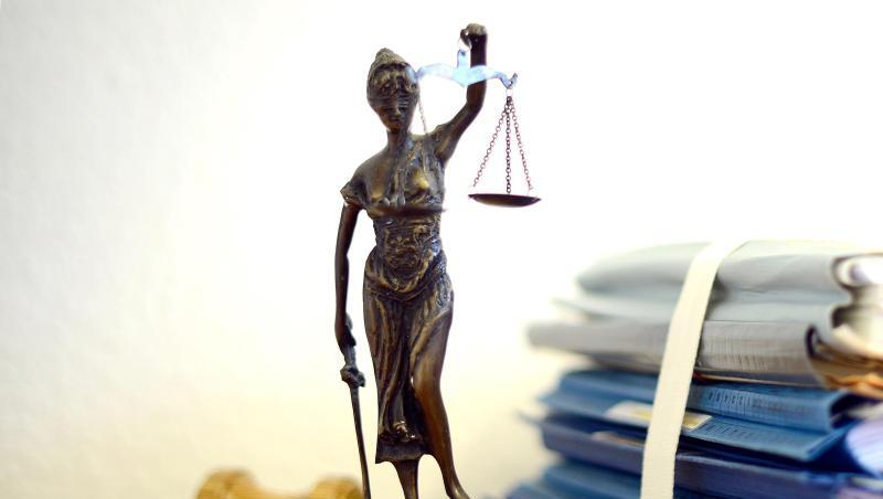 Die modellhafte Nachbildung der Justitia steht neben einem Holzhammer und einem Aktenstapel. Foto: Volker Hartmann/dpa/Symbolbild