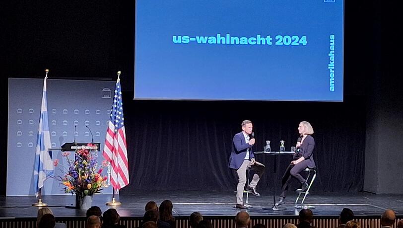 IHK Oberbayern-Chef Manfred Gößl (l) im Gespräch mit Moderatorin Christina Wolf vom Bayerischen Rundfunk auf der Bühne im Theatersaal des Amerikahauses in München. Er sieht große Gefahr für Bayern in Trumps hohen EU-Zöllen. IHK Oberbayern-Chef Manfred Gößl (l) im Gespräch mit Moderatorin Christina Wolf vom Bayerischen Rundfunk auf der Bühne im Theatersaal des Amerikahauses in München. Er sieht große Gefahr für Bayern in Trumps hohen EU-Zöllen.