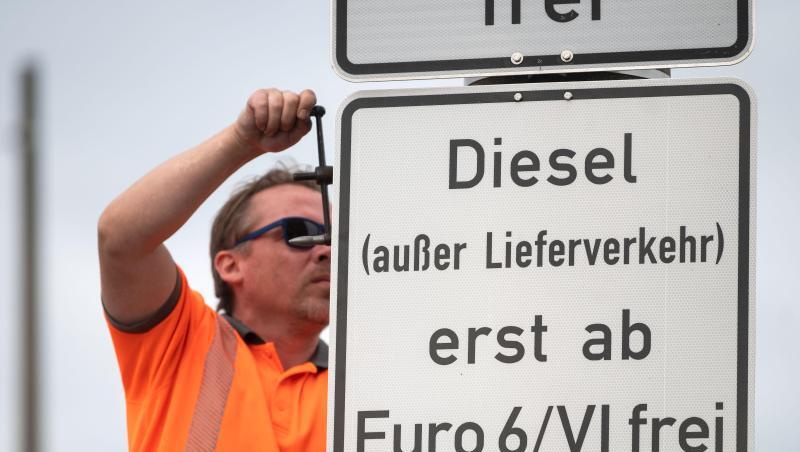 Ein Arbeiter hängt ein Schild auf, das auf ein Fahrverbot für Dieselfahrzeuge der Euronorm 5/V und schlechter hinweist.
