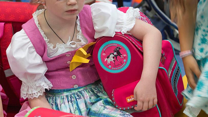 Ein Mädchen mit neuem Schulranzen wartet auf den Unterrichtsbeginn.