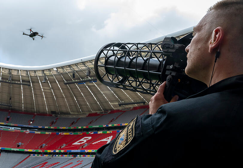 Ein speziell ausgebildeter Polizist zeigt während der Vorstellung des Münchner Sicherheitskonzepts zur Fußball-Europameisterschaft 2024 in der Allianz Arena eine kontrollierte Landung einer Drohne mithilfe eines Jammers. Ein speziell ausgebildeter Polizist zeigt während der Vorstellung des Münchner Sicherheitskonzepts zur Fußball-Europameisterschaft 2024 in der Allianz Arena eine kontrollierte Landung einer Drohne mithilfe eines Jammers.