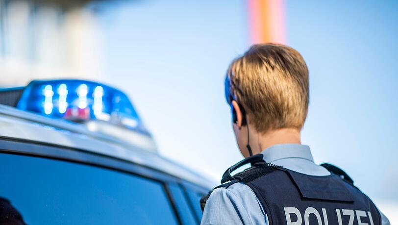 Eine Polizistin steht vor einem Streifenwagen. Eine Polizistin steht vor einem Streifenwagen.