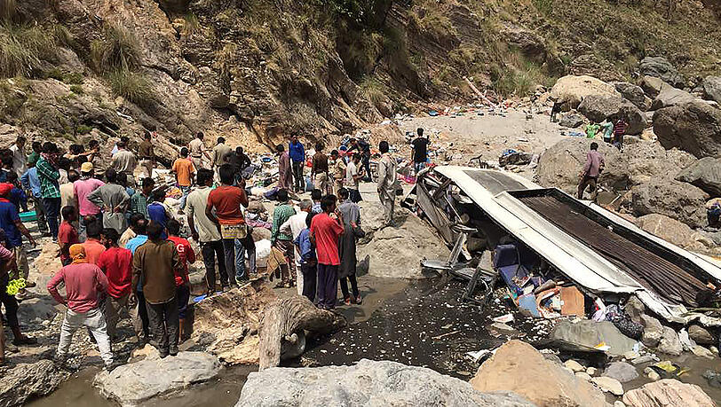 Helfer stehen in Chopal im indischen Bezirk Nerwa im Bundesstaat Himachal an der Unglücksstelle neben einem Bus, der zuvor in den Ausläufern des Himalaya-Gebirges von der Straße abgekommen war und hunderte Meter tief in den Fluss Tons gestürzt war. Helfer stehen in Chopal im indischen Bezirk Nerwa im Bundesstaat Himachal an der Unglücksstelle neben einem Bus, der zuvor in den Ausläufern des Himalaya-Gebirges von der Straße abgekommen war und hunderte Meter tief in den Fluss Tons gestürzt war.