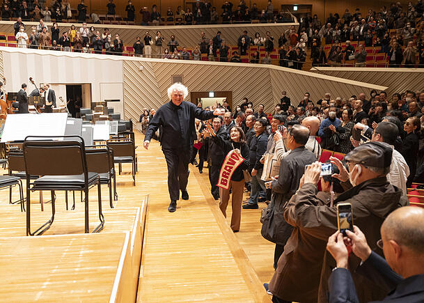Simon Rattle mit Fans nach dem Konzert in Kawasaki. Während der der Corona-Pandemie waren laute Rufe in japanischen Konzertsälen verboten, daher brachten manche Besucher Transparente mit und behielten dies bis heute bei. Ohnehin gilt in Japan lautes Geschrei als unhöflich. Simon Rattle mit Fans nach dem Konzert in Kawasaki. Während der der Corona-Pandemie waren laute Rufe in japanischen Konzertsälen verboten, daher brachten manche Besucher Transparente mit und behielten dies bis heute bei. Ohnehin gilt in Japan lautes Geschrei als unhöflich.