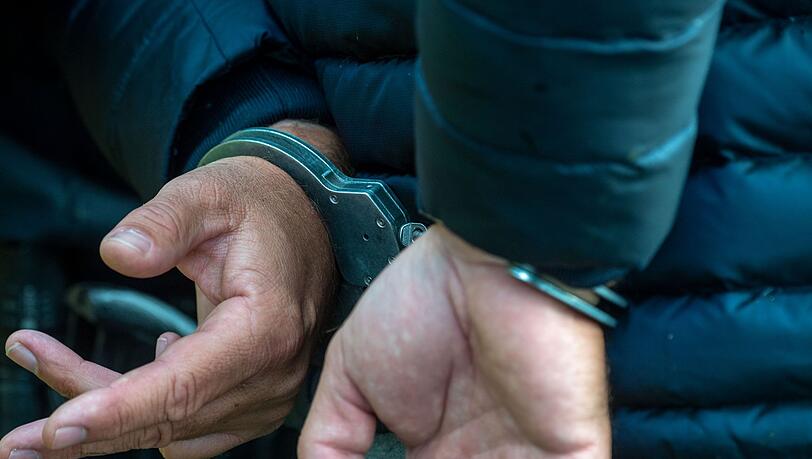 Ein Mann trägt Handschellen. (Symbolbild) Ein Mann trägt Handschellen. (Symbolbild)