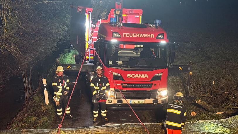 Feuerwehrleute bergen mit einem Kran einen umgestürzten Baumstamm. Feuerwehrleute bergen mit einem Kran einen umgestürzten Baumstamm.
