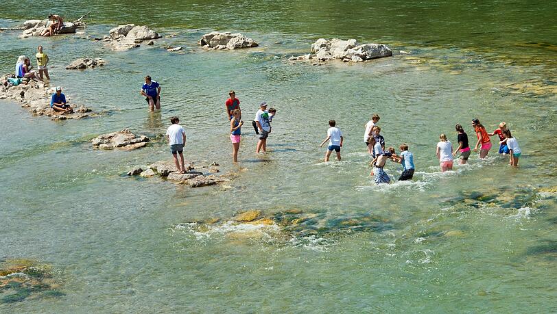 Eine Jugendgruppe watet durch das seichte grüne Wasser der Isar bei starker Strömung. Eine Jugendgruppe watet durch das seichte grüne Wasser der Isar bei starker Strömung.